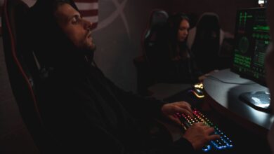 Young adults working on cybersecurity tasks in a dimly lit tech environment.