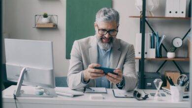 Senior businessman smiling while using smartphone at office desk.