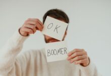 A person holding two cards with 'OK Boomer' written in bold text.