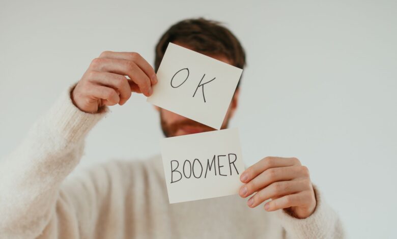 A person holding two cards with 'OK Boomer' written in bold text.