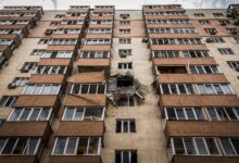 Low-angle view of a damaged apartment building in Kyiv, Ukraine with visible destruction.