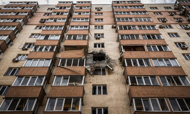 Low-angle view of a damaged apartment building in Kyiv, Ukraine with visible destruction.
