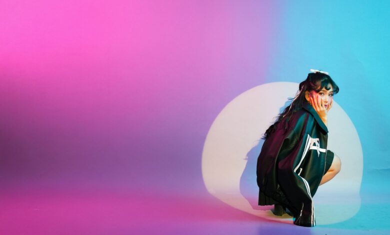 Vibrant studio portrait featuring a young woman surrounded by colorful lighting effects.
