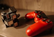 Close-up of a red game controller and 3D cube puzzle on a wooden surface.