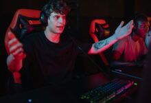 A dynamic image of focused gamers using headsets and RGB keyboards in an esports competition.