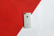 A silver smartphone placed on a contrasting red and white background captured from above.