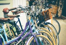 A row of colorful vintage bicycles with baskets parked on a sunny street, perfect for outdoor and lifestyle themes.
