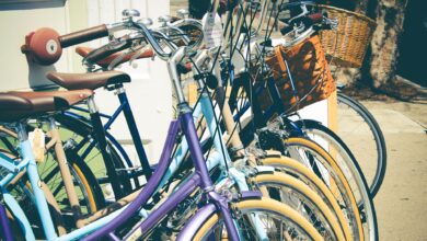 A row of colorful vintage bicycles with baskets parked on a sunny street, perfect for outdoor and lifestyle themes.