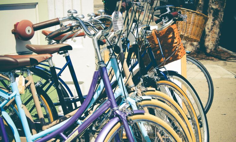 A row of colorful vintage bicycles with baskets parked on a sunny street, perfect for outdoor and lifestyle themes.