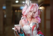 Dynamic cosplay portrait showcasing a pink-haired character with elaborate costume and accessories in a vibrant setting.