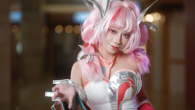 Dynamic cosplay portrait showcasing a pink-haired character with elaborate costume and accessories in a vibrant setting.