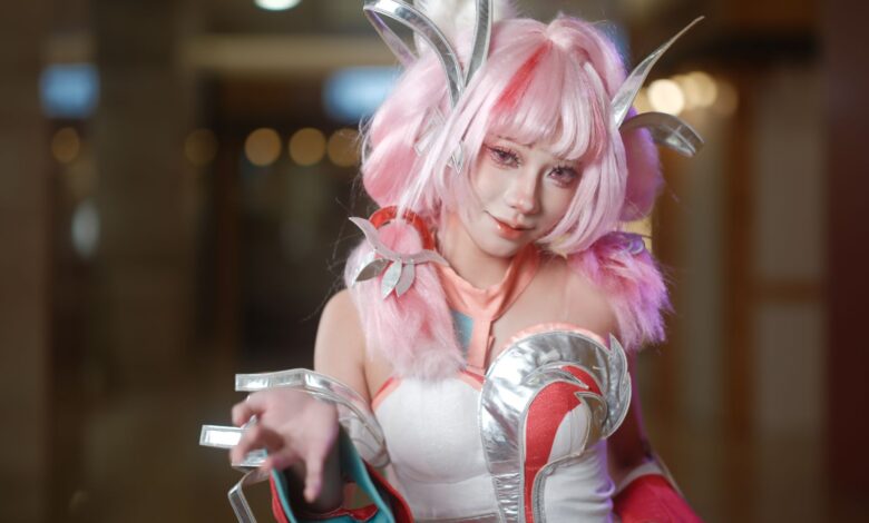 Dynamic cosplay portrait showcasing a pink-haired character with elaborate costume and accessories in a vibrant setting.