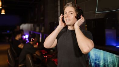 A man in a black shirt with headphones, enjoying gaming in a cyber cafe.