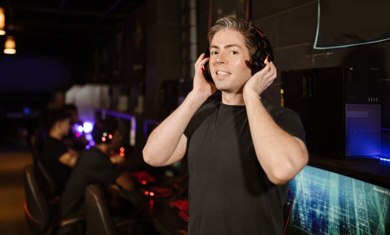 A man in a black shirt with headphones, enjoying gaming in a cyber cafe.