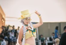 Cosplayer in vivid costume with yellow hat and accessories in an outdoor setting.