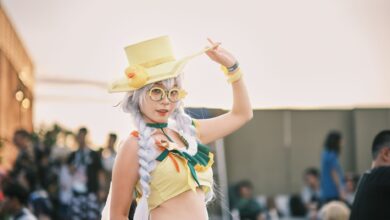 Cosplayer in vivid costume with yellow hat and accessories in an outdoor setting.