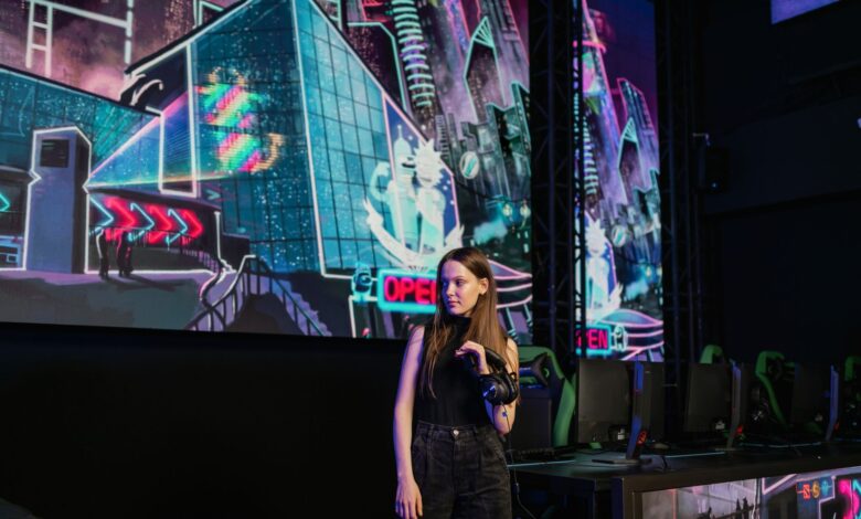 A woman stands in a virtual reality gaming arena with vibrant neon backdrops, wearing casual attire.