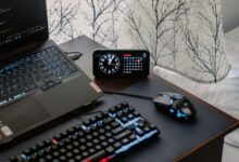 A modern workspace featuring a laptop, digital clock, gaming mouse, and keyboard, ideal for work and tech enthusiasts.