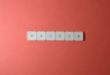 Close-up of the word 'HACKER' made with letter tiles on a red background, emphasizing cybersecurity.