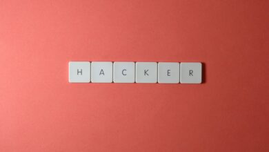 Close-up of the word 'HACKER' made with letter tiles on a red background, emphasizing cybersecurity.