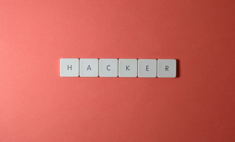 Close-up of the word 'HACKER' made with letter tiles on a red background, emphasizing cybersecurity.