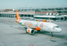 AirAsia airplane promoting sustainable ASEAN tourism parked at an airport.