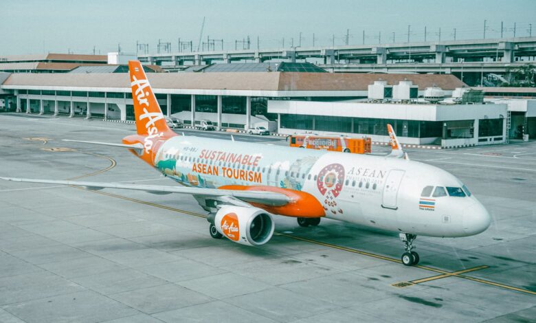 AirAsia airplane promoting sustainable ASEAN tourism parked at an airport.
