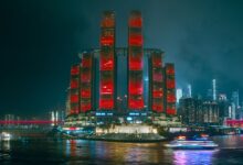 Illuminated skyscrapers reflecting in the river, showcasing Chongqing's modern cyberpunk skyline.
