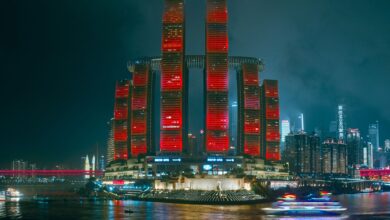 Illuminated skyscrapers reflecting in the river, showcasing Chongqing's modern cyberpunk skyline.