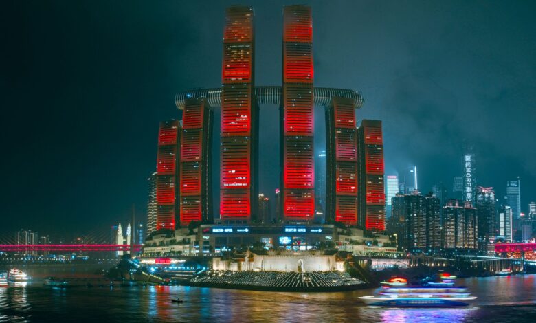 Illuminated skyscrapers reflecting in the river, showcasing Chongqing's modern cyberpunk skyline.
