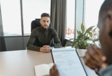 Professional man in turtleneck at office desk during an interview.