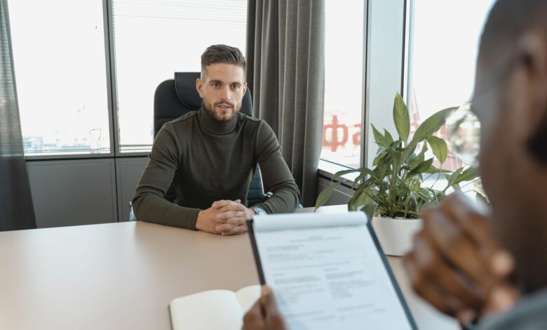 Professional man in turtleneck at office desk during an interview.