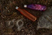 Creative top view of vibrant water bottles and nature-inspired elements on rugged ground.