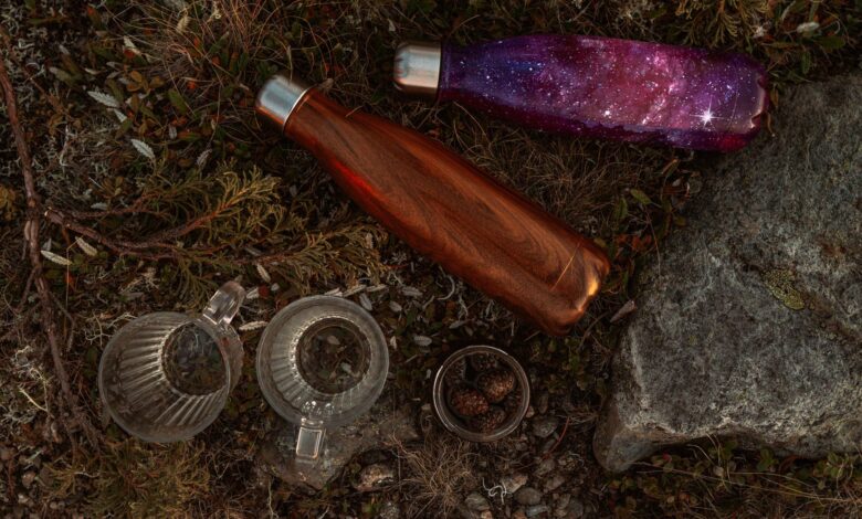Creative top view of vibrant water bottles and nature-inspired elements on rugged ground.