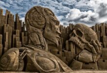 A monumental sculpture of a robot and skull set in Ringkøbing, Denmark, against a dramatic sky.