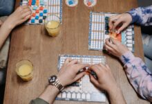 Close-up of hands and board game tiles during a fun gaming session indoors.
