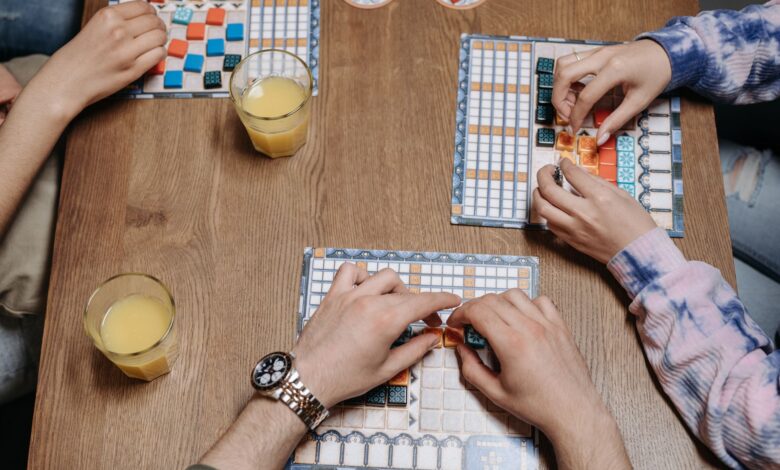 Close-up of hands and board game tiles during a fun gaming session indoors.