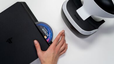 Close-up of a hand inserting a VR World's disc into a PlayStation with VR headset nearby.
