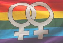 Rainbow flag with interlocking female symbols representing LGBTQ pride and inclusivity.