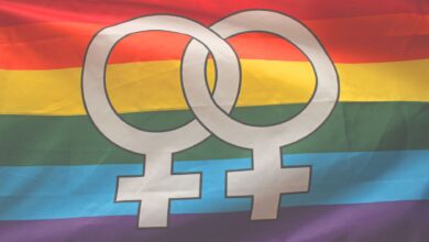 Rainbow flag with interlocking female symbols representing LGBTQ pride and inclusivity.