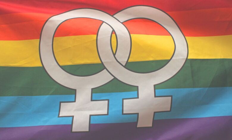 Rainbow flag with interlocking female symbols representing LGBTQ pride and inclusivity.