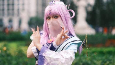 Cosplay enthusiast poses in colorful attire with lavender hair outdoors in Vietnam.