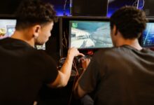 Two young men playing a multiplayer computer game at an arcade with enthusiasm and focus.