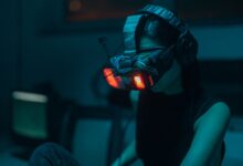 A woman in a dim-lit room wearing a neon-lit VR headset, creating a cyberpunk ambiance.