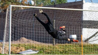 Dynamic action shot of a goalkeeper making a high save during a soccer game outdoors.
