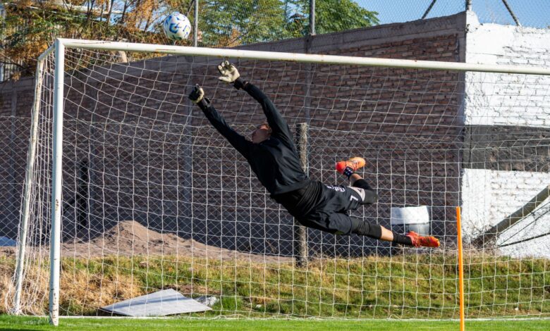 Dynamic action shot of a goalkeeper making a high save during a soccer game outdoors.