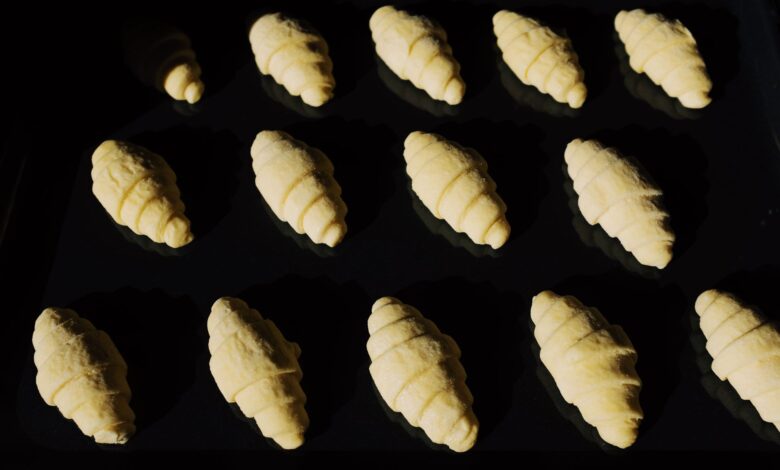 Fresh unbaked croissants aligned on a tray, capturing the essence of baking in progress.