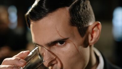 Close-up of a mysterious scarred man holding a glass, creating a noir atmosphere.