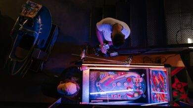 Overhead view of pinball game being set up in a retro arcade setting.