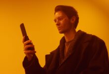 Dramatic studio portrait of a man using a vintage flip phone.